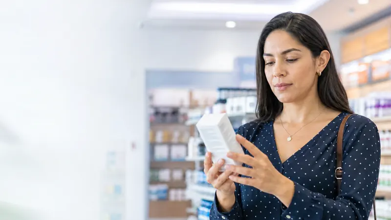 Mujer leyendo cuidadosamente la etiqueta de un complemento alimenticio